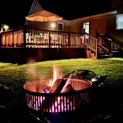 A cozy nighttime scene  with string lights glowing above the deck and a crackling firepit inviting you to gather under the stars.