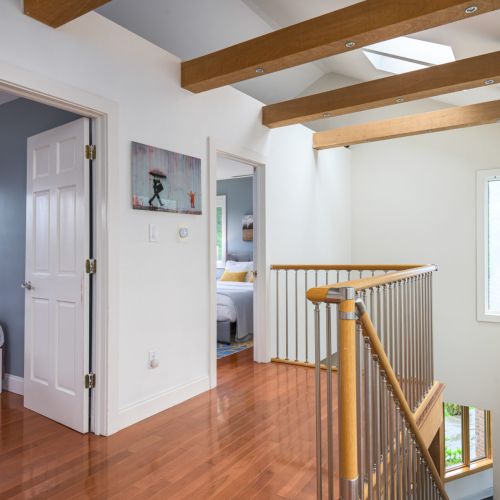 Bathed in natural light, the upstairs hallway leads to two cozy bedrooms and a shared bathroom - quiet, bright, and tucked away.