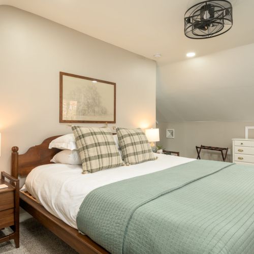 Serene and spacious, the primary suite features a king bed, cozy seating nook, and sweeping views of Lake Teedyuskung through the windows.