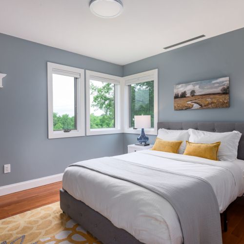 Simple, sunny, and thoughtfully styled - this queen bedroom features large windows and a full-length mirror for an easy, feel-good stay.