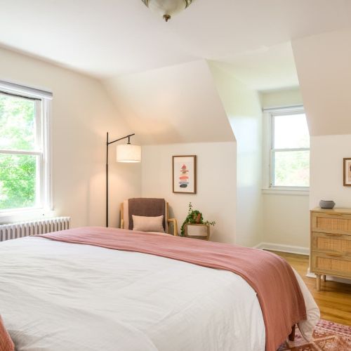 Large windows fill the room with natural light by day, while cozy bedding and thoughtful touches create a calming retreat by night.