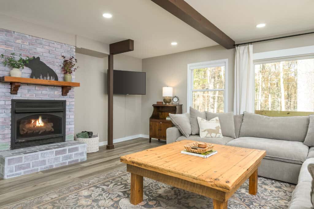 vacation rental management services calm neutral living room with sectional couch, fireplace and TV.
